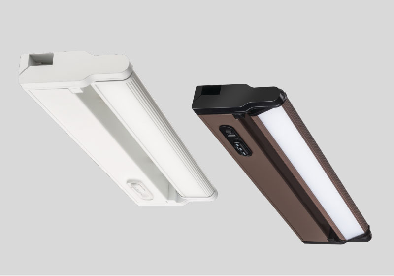 A rendering of two Juno Lighting UPLD LED undercabinet light fixtures in the white finish and bronze finish.